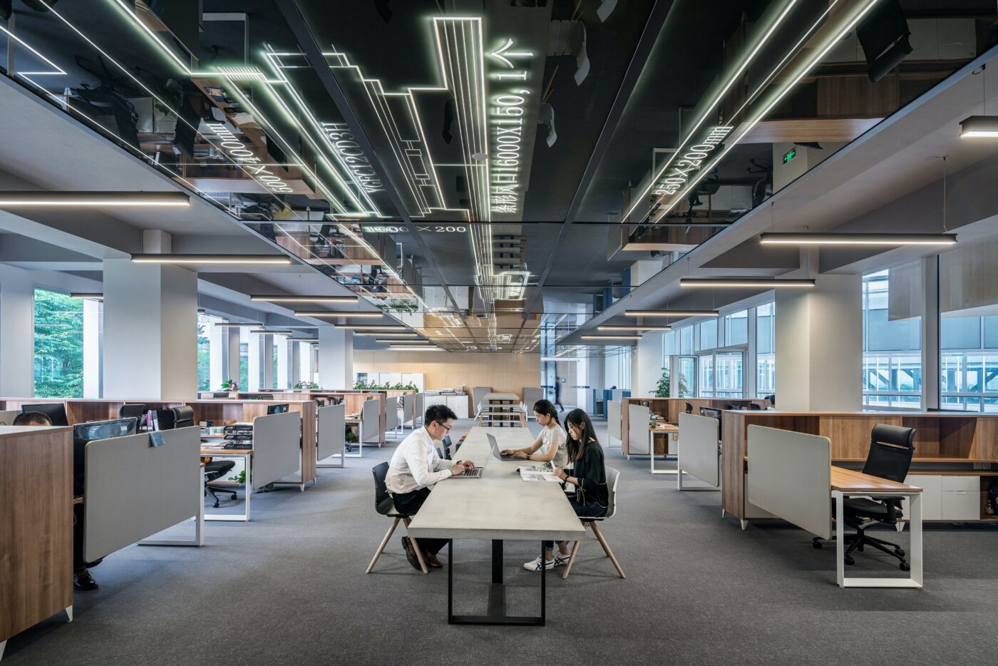 People working around a long table. On the ceiling, the building's energy systems are visible. 